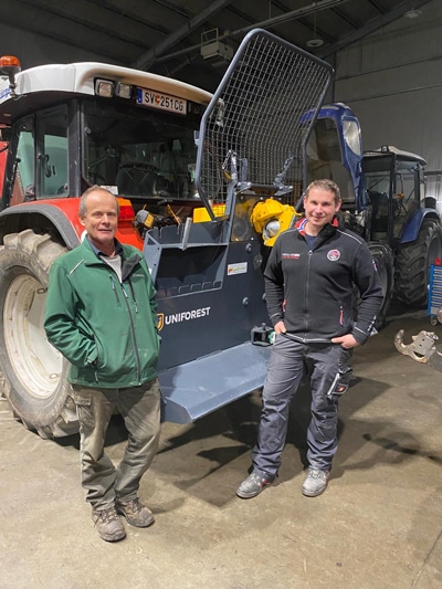 Zwei Männer in landwirtschaftlicher Werkstatt neben Traktor mit Uniforest-Seilwinde